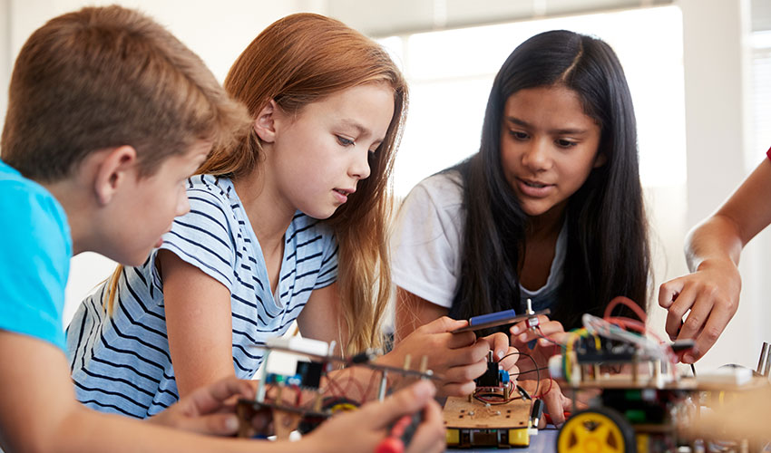 Students leaning over a table working as a team to put together a robotics project